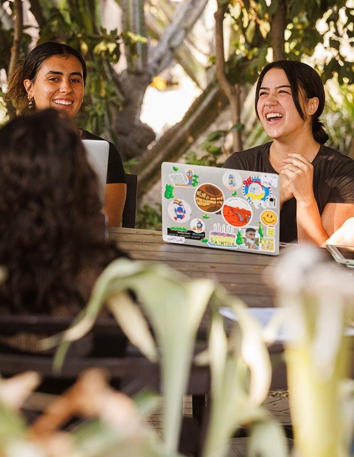 students discuss at an outside table