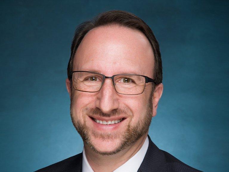 Close-up of Robert Fass with short brown hair and beard and wearing glasses.